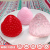 Three squishy toys shaped like strawberries in red, pink, and glitter colors displayed on a white plate.