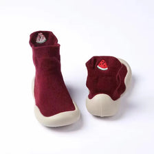 A pair of maroon baby first walker socks shoes with a small red fruit decoration.