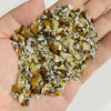 A handful of natural tumbled stone chips in shades of brown and yellow mixed with gray stones.