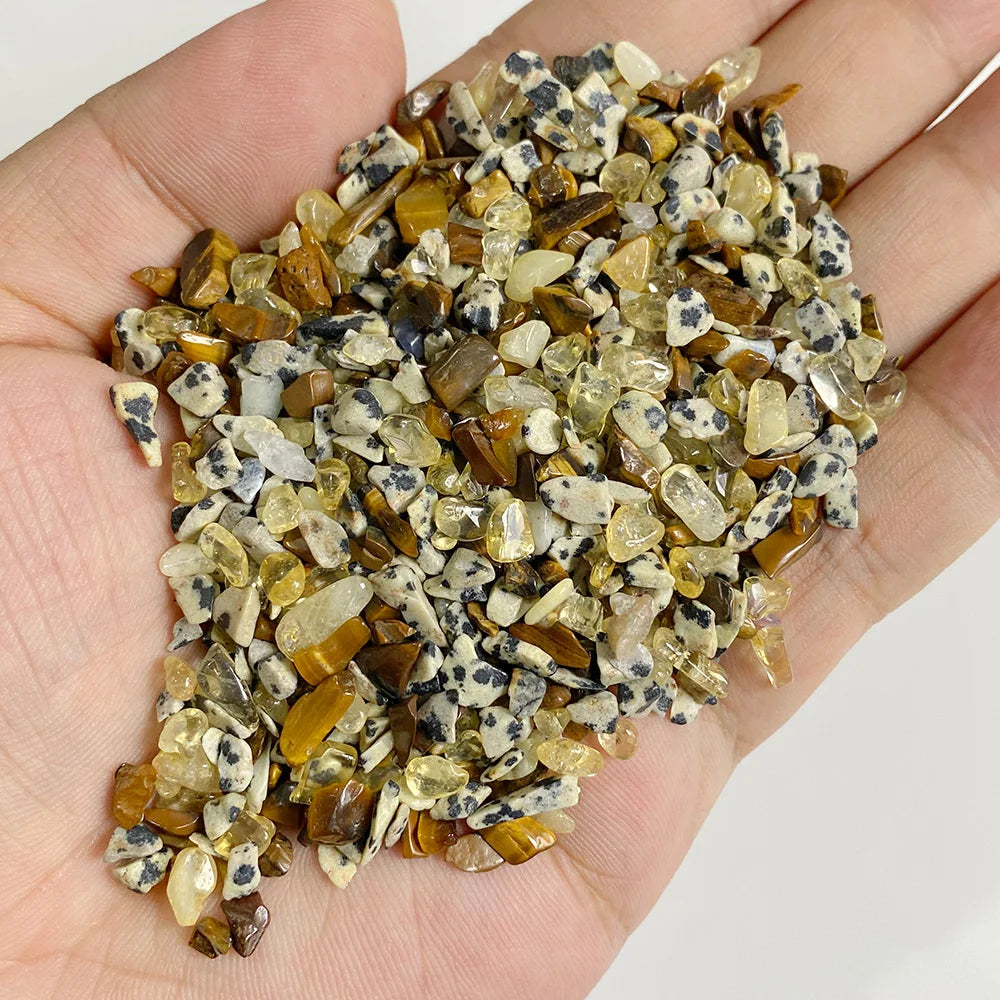 A handful of natural tumbled stone chips in shades of brown and yellow mixed with gray stones.