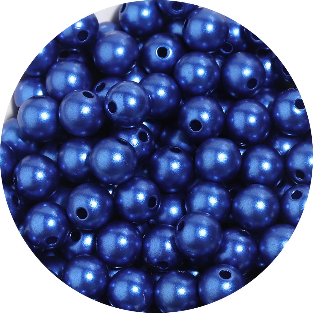 A close-up view of small, dark blue imitation pearl beads scattered in a pile.