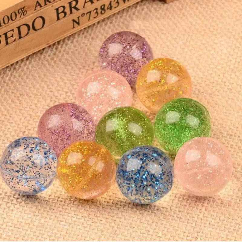 A collection of colorful glitter bouncy balls in various shades including pink, purple, yellow, green, and blue