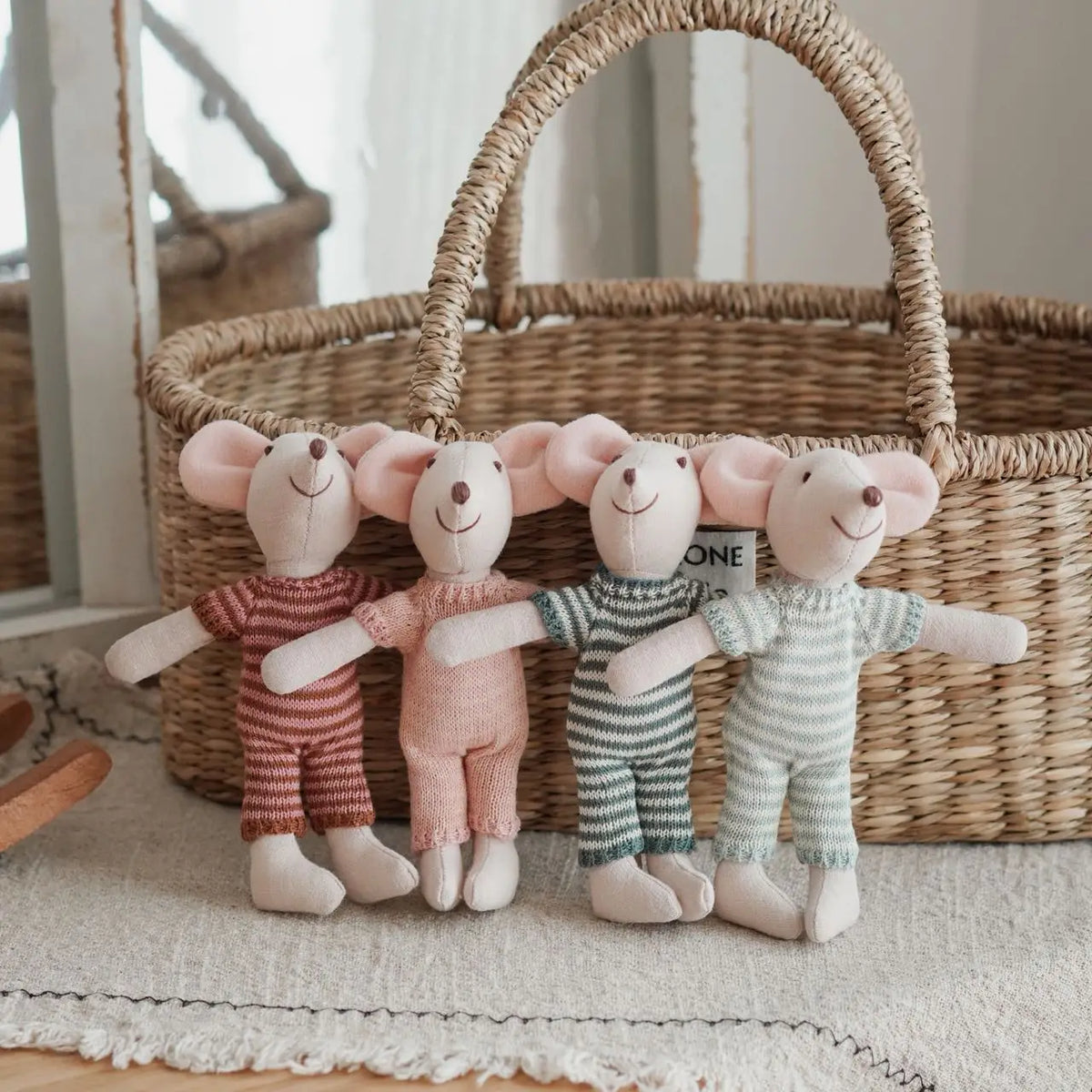 Four handmade mouse plush dolls wearing retro outfits standing in front of a woven basket