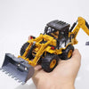A hand holds a yellow diecast construction vehicle excavator with a black bucket and yellow tracks.