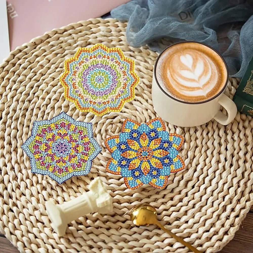 A set of eight colorful mosaic coasters and a holder displayed on a woven mat next to a latte.