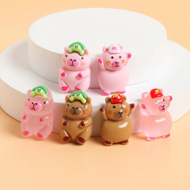 A collection of pink and beige resin figurines shaped like capybaras with green accents displayed on a white circular stand.