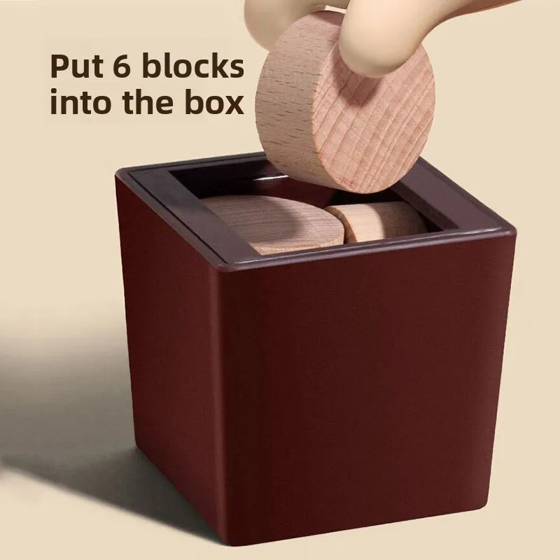 A hand is putting six wooden blocks into a dark brown box for a puzzle challenge.