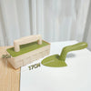 A light green plastic beach sand castle building tool set showing a mold and a shovel on a white surface.