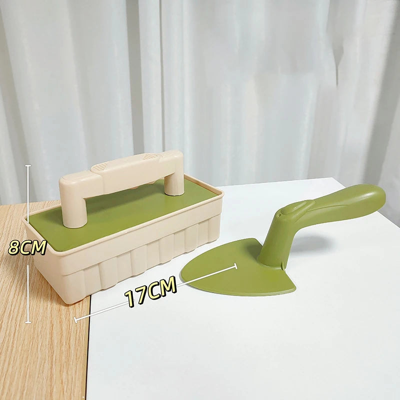 A light green plastic beach sand castle building tool set showing a mold and a shovel on a white surface.