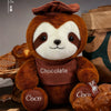 A brown sloth plush toy with white markings and a chocolate-colored chest, sitting on a wooden surface.