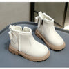 A pair of white cozy kids winter boots with faux leather finish resting on a gray surface.