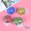 Three colorful squeeze stress relief balls in blue, yellow, and green with mesh netting on a pink background.