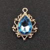 Gold plated water droplet charm featuring a blue crystal rhinestone set in an ornate flower design.