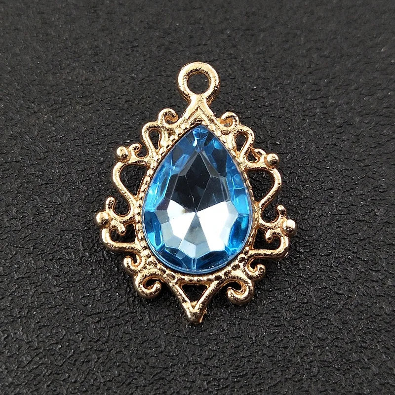Gold plated water droplet charm featuring a blue crystal rhinestone set in an ornate flower design.