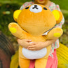 A child is holding a yellow Rilakkuma anime plush bear with large eyes outdoors.