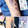 A close-up of a person's arm displaying colorful glitter mermaid temporary tattoos and a sheet of the product packaging.
