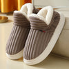 A pair of brown faux fur slippers with white soles and fluffy trim resting on a light surface.
