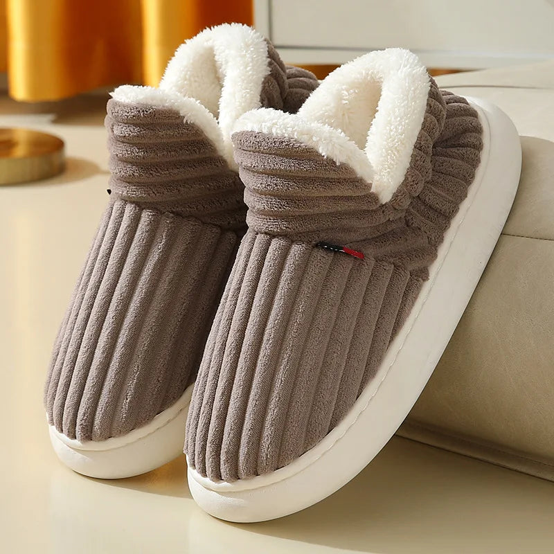A pair of brown faux fur slippers with white soles and fluffy trim resting on a light surface.