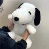 A person is holding a white Snoopy cartoon plush toy with black ears against a light background.