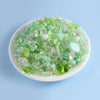 A pile of clear and green acrylic beads mixed with white beads for DIY jewelry making