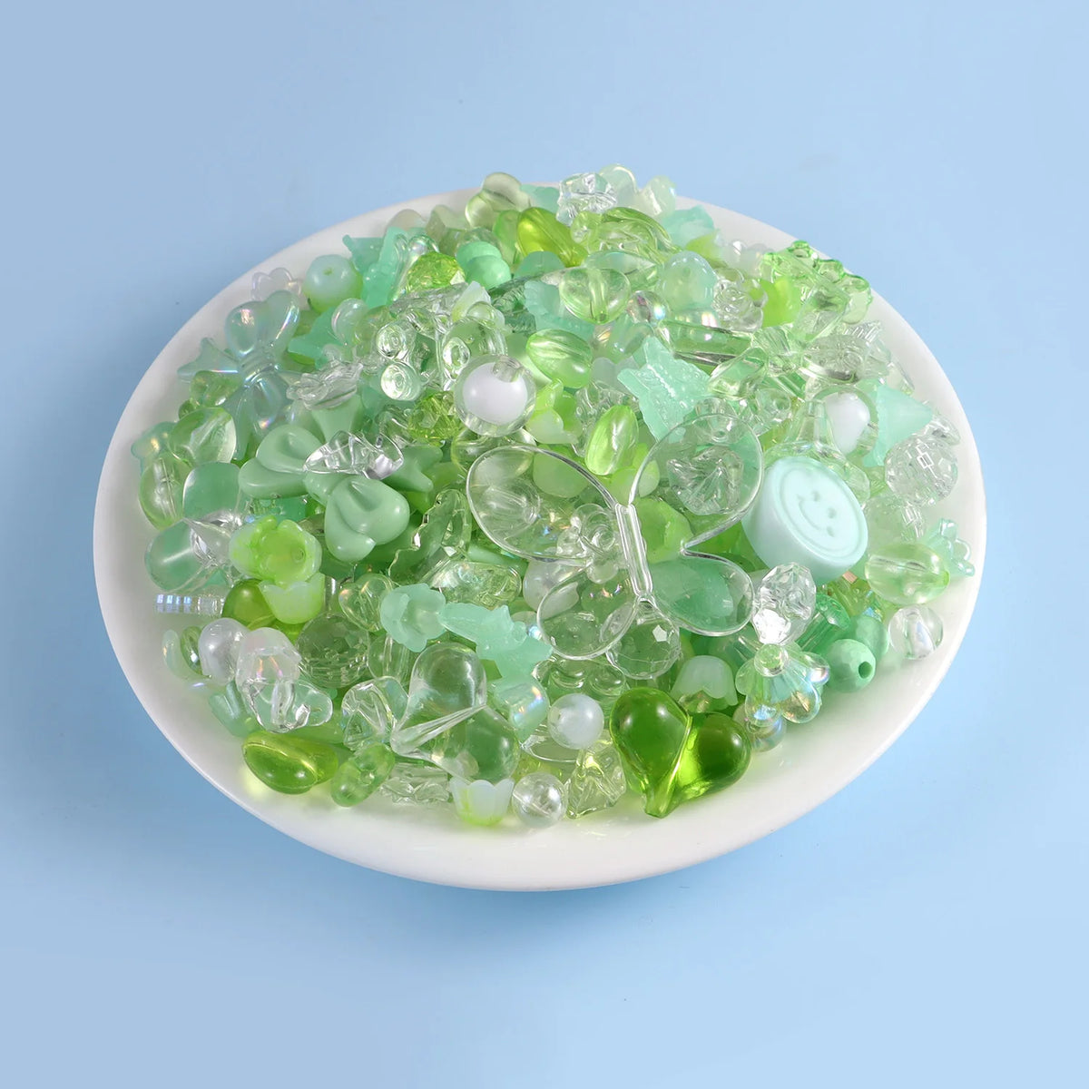 A pile of clear and green acrylic beads mixed with white beads for DIY jewelry making