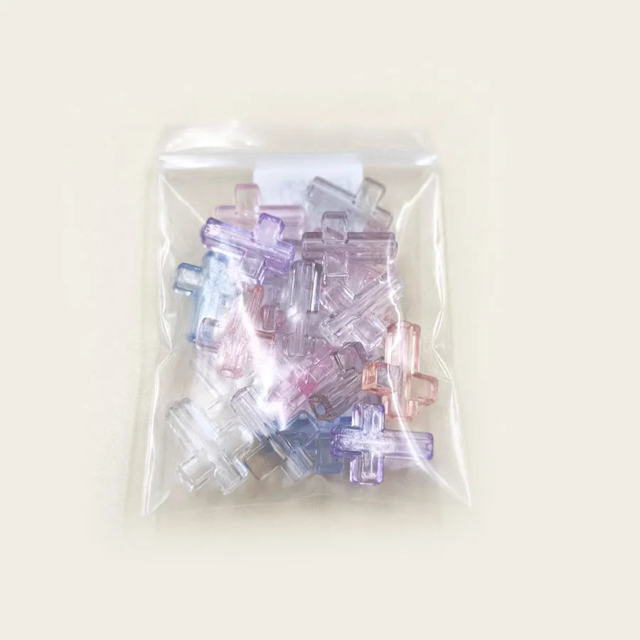 A clear plastic bag filled with colorful acrylic cross beads for jewelry making