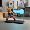 A figurine of Son Goku performing a Kamehameha attack with a bright blue light effect on a black base.