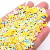A hand holds a pile of yellow and pastel colored polymer clay slices for DIY crafts