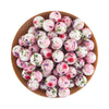 A wooden bowl filled with pink and white silicone beads for jewelry making.