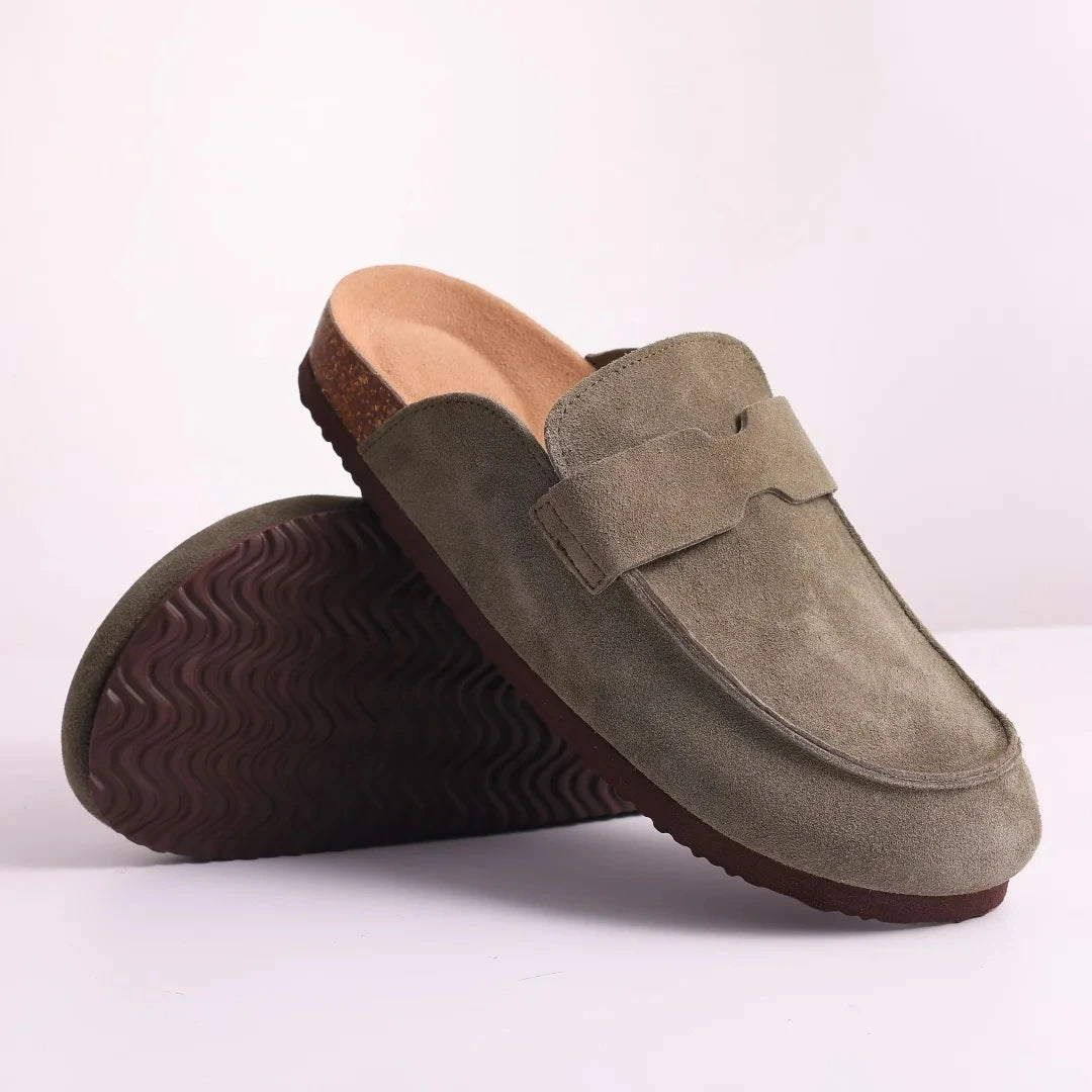 A pair of olive green suede cork mules shown with the sole visible.