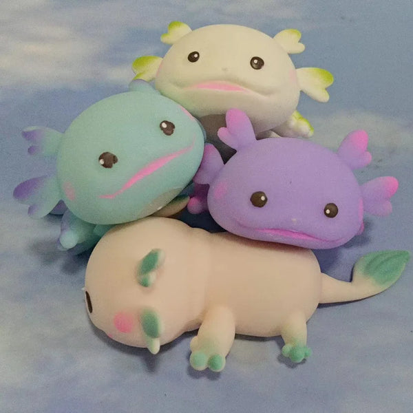 A set of four squishy toys shaped like axolotls in various colors including light blue, white, and purple.
