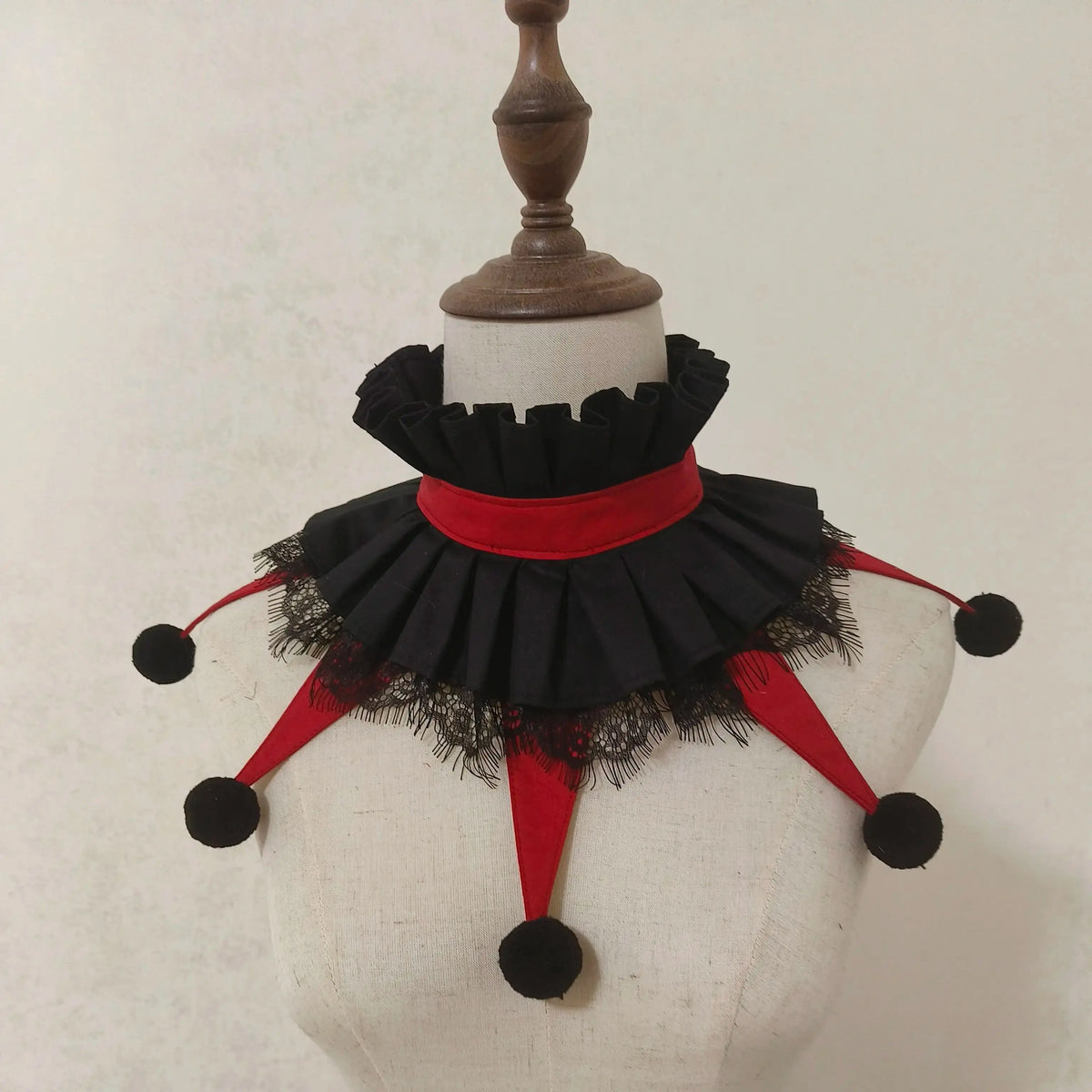 Black and red ruffled collar accessory displayed on a mannequin neck.
