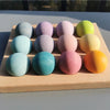 A wooden tray holds ten colorful, spherical sensory music trees with marble runs arranged in a row.