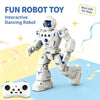 A white dancing robot toy standing on a blue surface with a white remote control visible nearby.