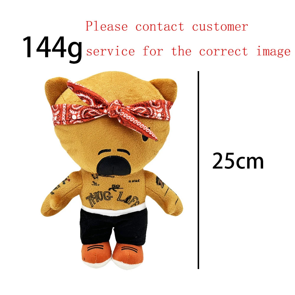 A tan teddy bear plush doll wearing a red patterned ribbon and black clothing.