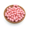 A wooden bowl filled with pink silicone round beads for jewelry making and DIY crafts