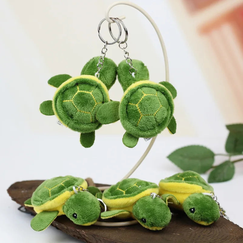 A set of twelve adorable mini sea turtle plush toys in green and yellow are displayed on a wooden surface.