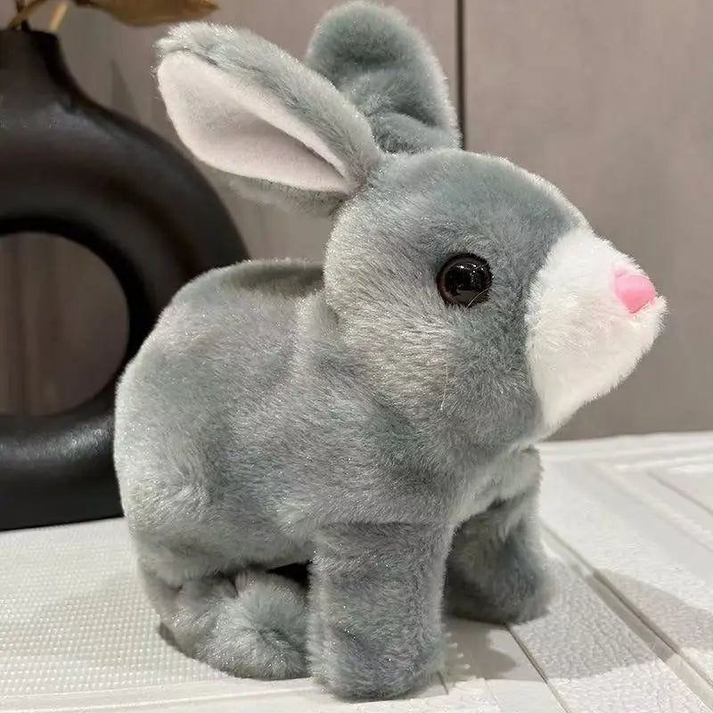 A gray and white plush rabbit toy with large ears sitting on a white surface.