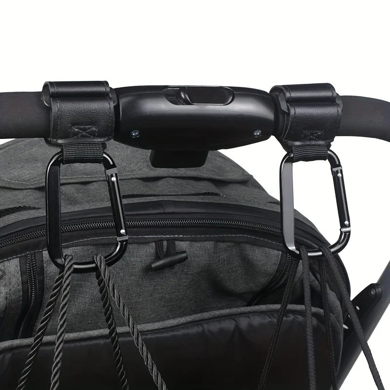 Close-up of black heavy-duty stroller hooks attached to a black fabric bag or stroller handle.