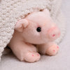 A pink plush pig stuffed animal with black eyes is nestled inside a cream-colored knitted fabric.
