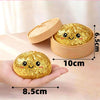 A hand holds a golden glitter dumpling squishy toy with an accompanying lid, showing its size and texture.
