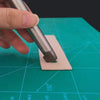A hand is using a metal punch tool to create a hole in a piece of light pink leather for crafting.