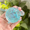A hand holds a clear, iridescent blue turtle stress relief fidget ball with sparkling star inclusions.