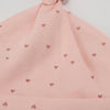 A light pink knitted baby hat with small heart embroidery on the crown and brim.