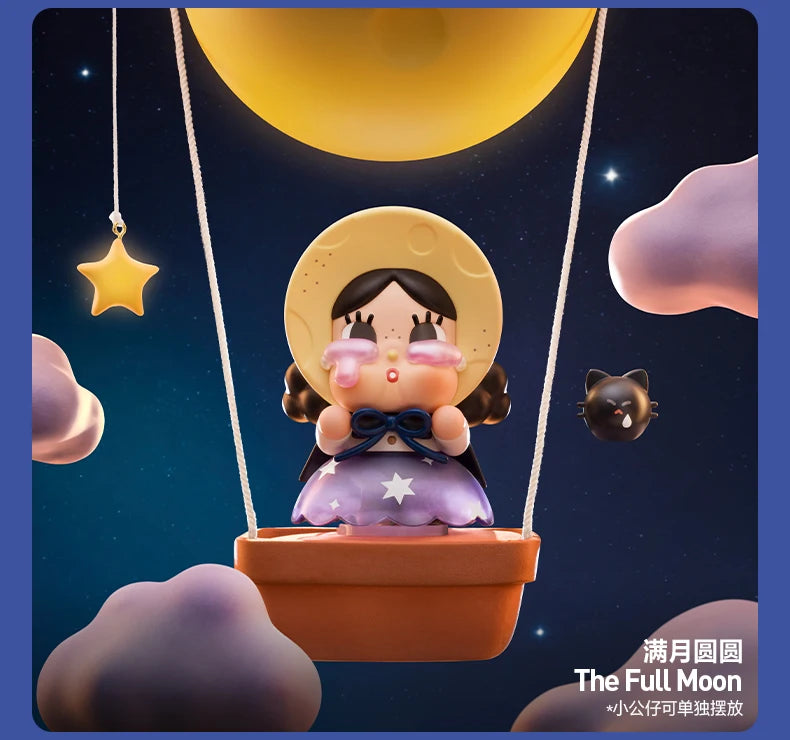 A collectible figurine of a crying girl with a yellow hat suspended by strings under a large moon in a dark night sky.