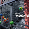 A green moon ball is visible against a dark metal fence with a red background.