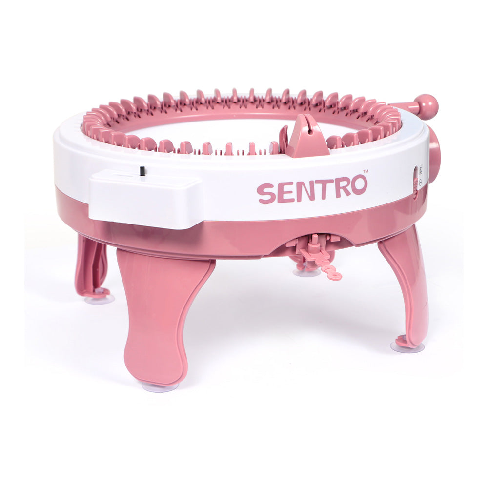 A pink manual knitting machine for hats and scarves, shown from the side.
