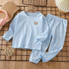 Light blue striped long sleeve cotton pajama set for kids lying on a wooden grid surface.