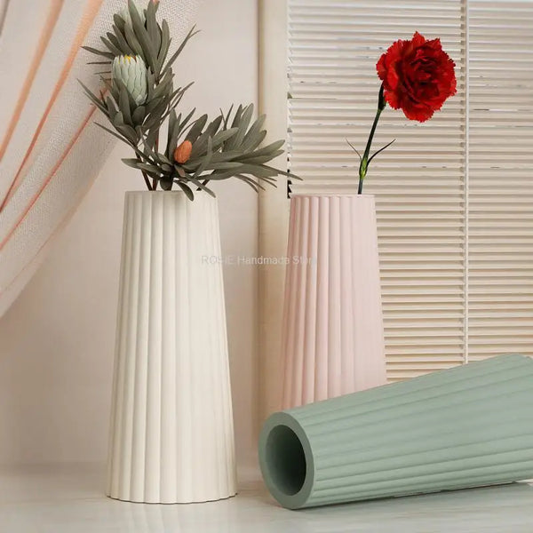 A white silicone mold for epoxy and concrete flowers stands next to a pink one and a red rose.