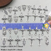 A collection of vintage antique silver cross charms and pendants for jewelry making displayed on a ruler.